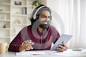 Distance Learning. Indian Man In Headphones Watching Educational Webinar On Digital Tablet