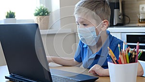 Distance learning online education. Cute caucasian boy doing homework on a computer while quarantine epidemia corona