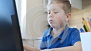 Distance learning online education. Cute caucasian boy doing homework on a computer while quarantine epidemia corona