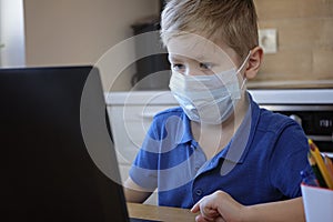 Distance learning online education. Cute caucasian boy doing homework at home while quarantine of epidemia corona virus