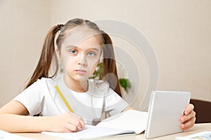 Distance learning online education.School girl does homework on tablet at home. Quarantine