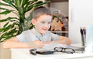 Distance learning online education. A schoolboy is studying at a computer at home and doing school homework. quarantine