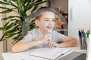 Distance learning online education. A schoolboy is studying at a computer at home and doing school homework. quarantine