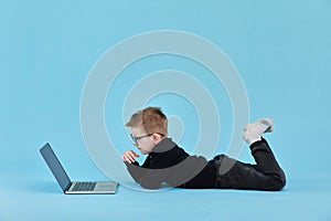 Distance learning online education. Schoolboy studying at home with laptop and doing school homework on blue background
