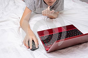 Distance learning online education, schoolboy studying at home while lying in bed with a laptop and doing school homework. e-