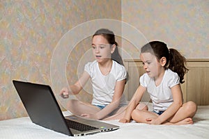 Distance learning online education. Schoolgirl and her sister studying at home with digital tablet laptop notebook