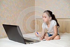 Distance learning online education. Schoolgirl studying at home with digital tablet laptop notebook