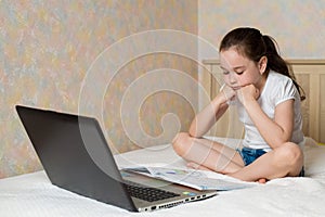 Distance learning online education. Schoolgirl studying at home with tablet laptop notebook and doing school homework