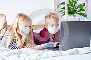 Distance learning online education. Sickness school boy and girl in medical mask studying at home with digital tablet photo