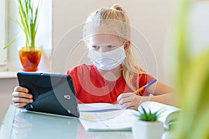 Distance learning online education. Sickness schoolgirl in medical mask studying at home with digital tablet in hand and photo