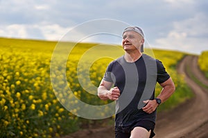 Distance runner running on a road through canola field