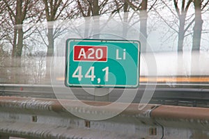 Distance sign in kilometers at motorway A20 at 44,1 kilometer on left side of the road, with speed lines of passings car.