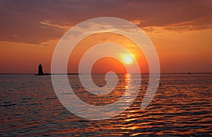 A distance silhouette of the lighthouse and a boat during sunset at Cape Henlopen State Park, Lewes, Delaware, U.S