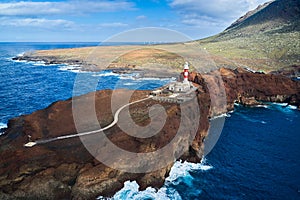 a distant cape on the edge of an island on the Atlantic Ocean with a lighthouse