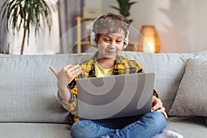 Distant friendship. Talkative little boy enjoying online communication with friend, talking via laptop and headphones