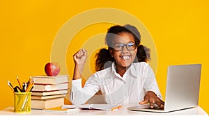 African American School Girl At Laptop Raising Hand, Yellow Background photo