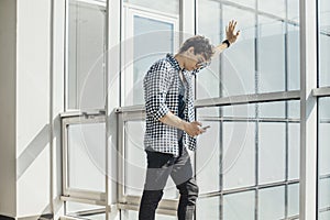 Distant plan of young man looking at mobile phone screen at metro station.