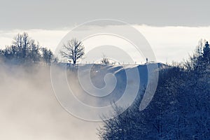 Distant snowy ridge and hiker enjoying the view of valley in fog below