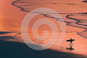 Distant surfer silhouette in the shore at sunset photo