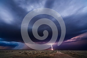 Distant thunderstorm lightning strike over a dirt road