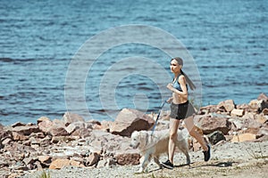 distant view of asian female jogger running with dog