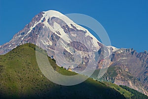 Distant view on Gergeti Trinity Church in Stepansminda, Georgia. Clear sky above the snow-capped Mount Kazbegi in the