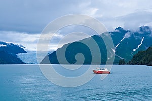 Distant view of a Holgate glacier with red boat in the foreground in Kenai fjords National Park, Seward, Alaska, United States,