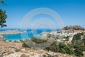 Distant view at Lindos Town and Castle with ancient ruins of the Acropolis on sunny warm day. Island of Rhodes, Greece. Europe