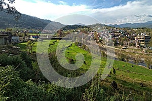 Distant view of lush green terraced rice field near village Baijnath and River Gomati