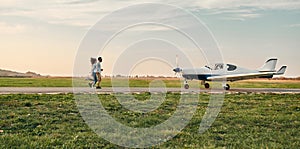 Distant view of stylish young couple holding hands and running on small airplane