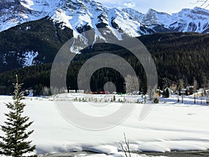 A distant view of the town of Field, in British Columbia Canada, during winter. The landscape is covered in snow and the rocky mou