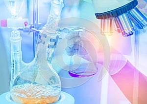 Distillation set with dropping funnels is separating the component substances from liquid mixture with hand scientist holding flas