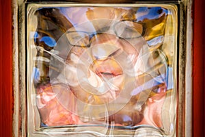 Distorted Girl Face Through Glass Block