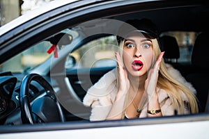 Distracted fright face of a woman driving car, wide open mouth eyes holding wheel side window view. Negative human face expression