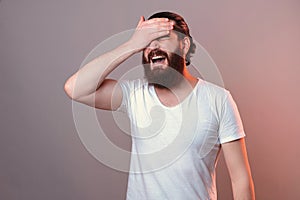 Distraught bearded man is giving himself a facepalm as he forgot something.
