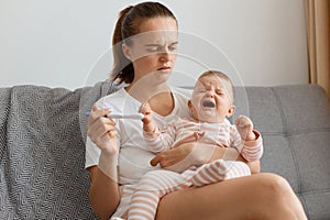 Distraught dark haired woman with pigtail waiting for pregnancy test result thinking about future while sitting on sofa in living