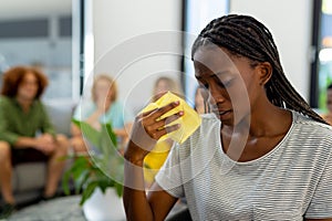 Distressed african american woman holding tissue and crying in group therapy session