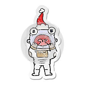 distressed sticker cartoon of a alien gasping in surprise wearing santa hat