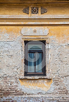 The distressed surface of the old buildingÃ¢â¬â¢s exterior with an antique window