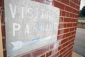 Distressed Visitors Parking Sign on an old brick wall.