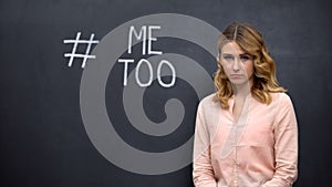 Distressed woman standing near Metoo hashtag, movement against sexual assault