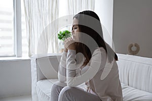 Distressed young female sitting on couch meeting morning with tears