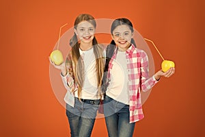 Distributing free fresh fruit at school. Girls kids casual style eat apple fruit orange background. Schoolgirls eat