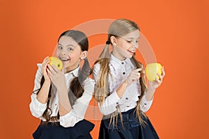 Distributing free fresh fruit at school. Girls kids school uniform orange background. Schoolgirls eat apples. School