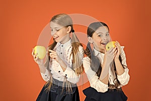 Distributing free fresh fruit at school. Girls kids school uniform orange background. Schoolgirls eat apples. School