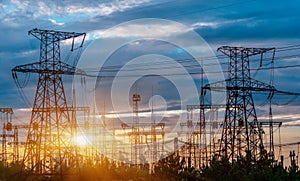 Distribution electric substation with power lines and transformers, at sunset.