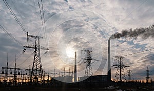 Distribution electric substation with power lines and transformers, at sunset