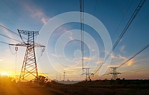 Distribution electric substation with power lines and transformers, at sunset