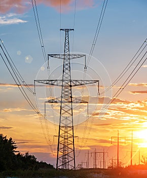 Distribution electric substation with power lines and transformers, at sunset