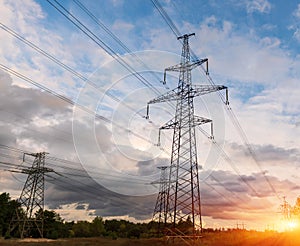 Distribution electric substation with power lines and transformers, at sunset